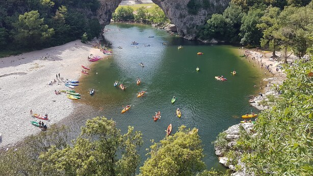 A river with kayaks and people on the shore, surrounded by cliffs and trees. - VERY NICE GITE 4 PEOPLE CENTER VALLON PONT D'ARC (Vallon-Pont-d'Arc)