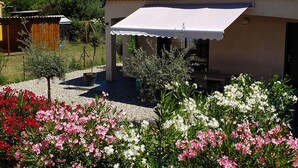 A house with a tiled roof, a covered porch, and a garden with flowering plants. - VERY NICE GITE 4 PEOPLE CENTER VALLON PONT D'ARC (Vallon-Pont-d'Arc)