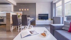 Ein modernes Wohnzimmer mit Essbereich, Küche und Fernseher.