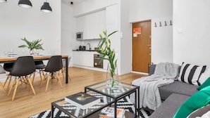 A modern living room with a sofa, a coffee table, and a dining area with chairs and a table.