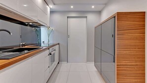Una cocina moderna con armarios blancos, encimera de madera y pileta de acero inoxidable.