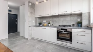 A modern kitchen with white cabinets, a built-in oven, and pendant lighting. - Bright Apartment in the Center | Balcony and 2 Bedrooms (Warszawa)