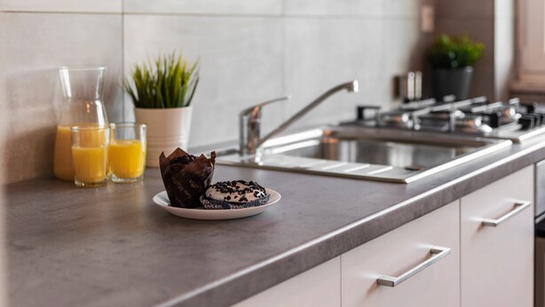 A kitchen counter with a plate of muffins, a glass of orange juice, and a potted plant. - Bright Apartment in the Center | Balcony and 2 Bedrooms (Warszawa)