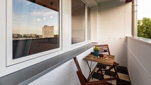 A balcony with a wooden table, chairs, and a potted plant. - Bright Apartment in the Center | Balcony and 2 Bedrooms (Warszawa)
