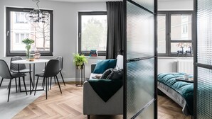 A modern room with a dining table, chairs, a sofa, and a bed. - Green and blue apartments (Gdansk)