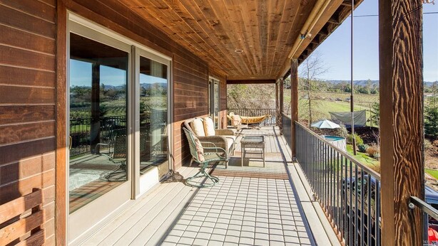 Eine Holzterrasse mit einer Glastür, die zu einer Terrasse führt.