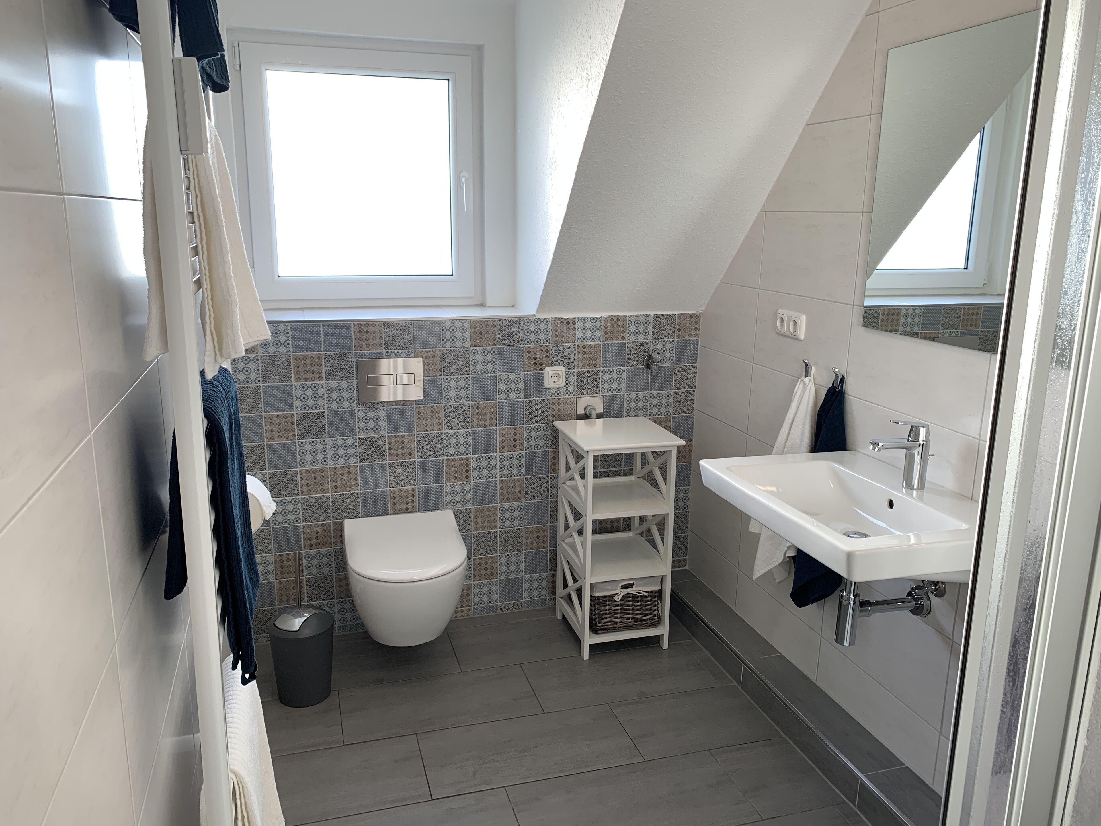 Ein modernes Badezimmer mit Toilette, Waschbecken und einem kleinen Fenster.