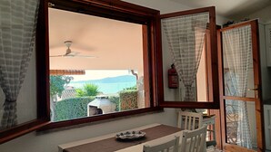 Una habitación con un ventanal grande, un ventilador de techo, una mesa con un tazón y una silla.