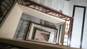 A marble staircase with a wooden handrail and a view of a room below. - Sydna All Hussain Hotel (Cairo)