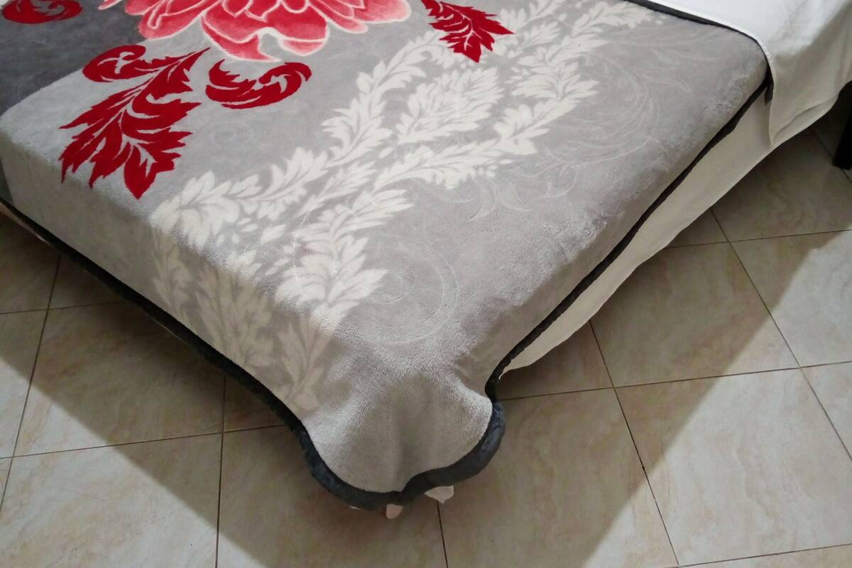 A bed with a floral-patterned bedspread and white pillows.