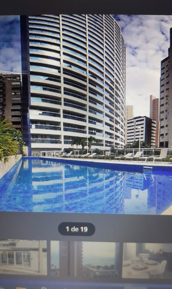 Un hotel moderno con piscina, varias plantas y vistas a la ciudad.
