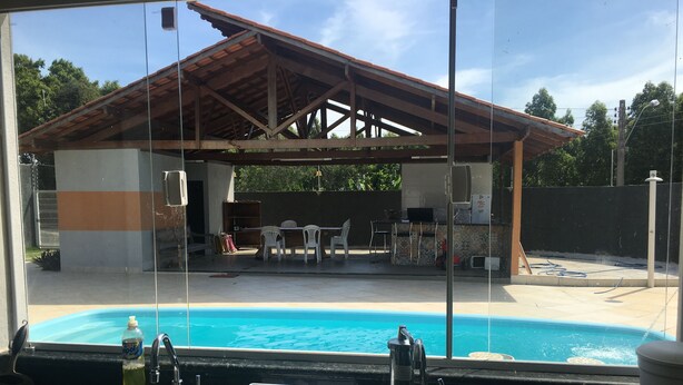 Udsigt over poolen med en overdækket patio, udendørs møbler og et synligt køkkenområde.