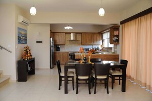 A modern kitchen with wooden cabinets, a central island, and a dining area with a table and chairs.