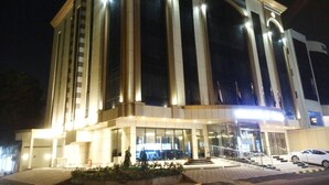 Un bâtiment moderne doté d’une entrée imposante, de grandes fenêtres et d’une façade bien éclairée la nuit.