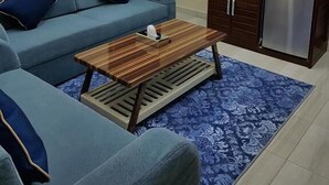 Un salon moderne avec un canapé bleu, une table basse en bois et un tapis à motifs.