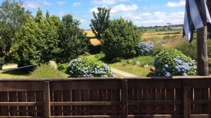 A garden with a wooden fence, a pathway, and a view of the countryside. - - Ti Nominoë Cottage - (Lannilis)