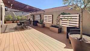 A wooden deck with a table and chairs, surrounded by planters and a pergola. - Bright 100m2 apartment in Provence with terrace (Sénas)