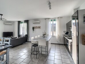 A modern kitchen with a dining area, white appliances, and a large window.