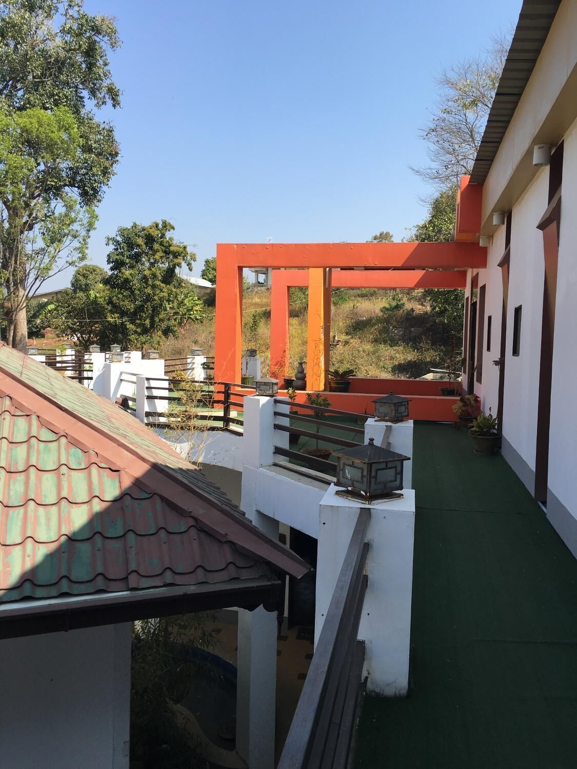 Un espace extérieur abrité doté d’un sol vert, de murs blancs et d’une structure orange.