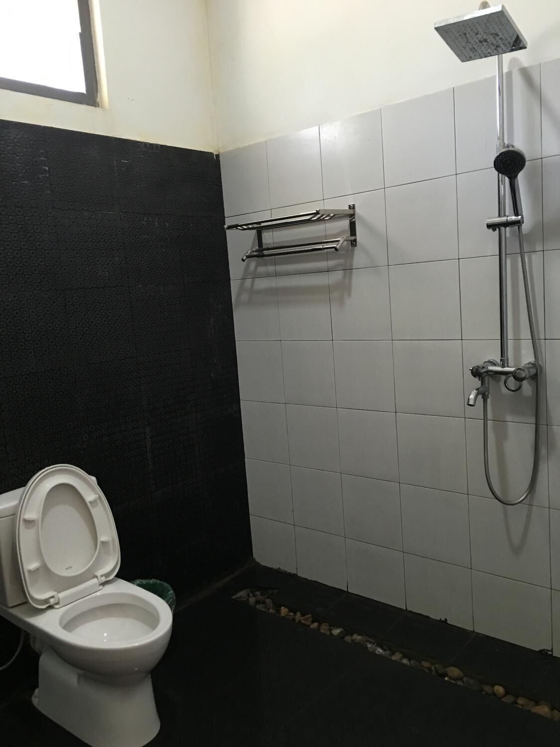 A bathroom with a toilet, a shower, and a towel rack.