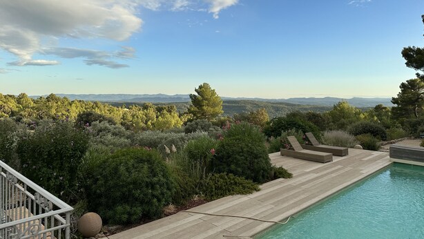 Una piscina con vistas a montañas y un cielo despejado.