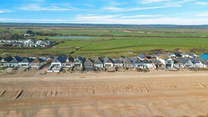 Un área residencial costera con casas alineadas a lo largo de la playa, una playa de arena y vista al mar.