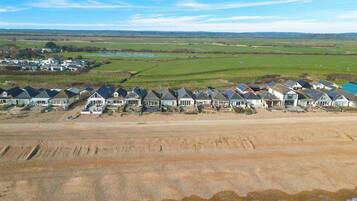 Une zone résidentielle côtière où les maisons sont alignées le long du rivage, avec une plage de sable et une vue sur la mer.