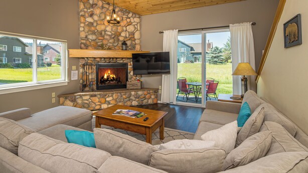 Una sala de estar acogedora con una chimenea de piedra, un sofá grande y un televisor de pantalla plana.