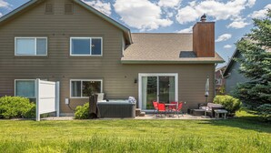 Una casa de dos pisos con un patio que tiene mobiliario exterior y un jacuzzi.
