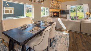 Un comedor con una mesa de madera oscura, sillas blancas tapizadas y una chimenea de piedra.