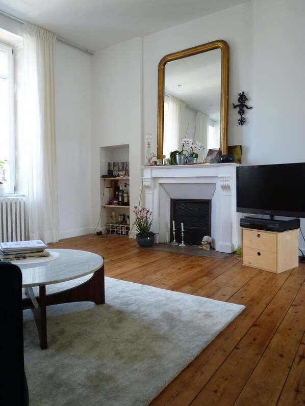 Ein Wohnzimmer mit Kamin, großem Spiegel und Fernseher.