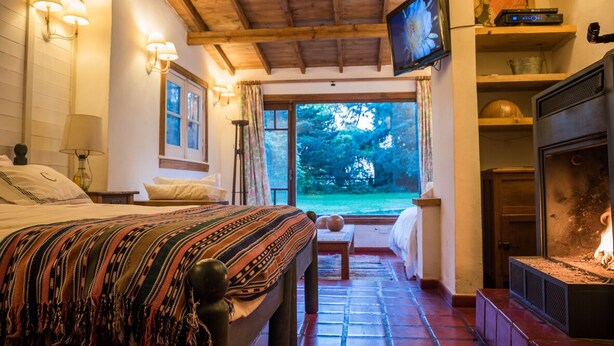 Ein Schlafzimmer mit einem großen Bett, einem Kamin und Blick ins Freie.