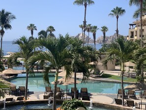 Zona de piscina con palmeras, sillas de descanso y vistas al mar.