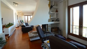 A spacious living room with a fireplace, a sofa, a coffee table, and a bookshelf.