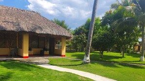 A thatched-roof building with a paved pathway leading to it, surrounded by well-maintained grass and palm trees. - Hidden Paradise Beach Jiote (Moyuta)