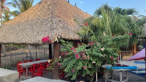 A thatched-roof hut with outdoor seating and a pool area. - Hidden Paradise Beach Jiote (Moyuta)