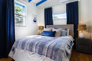 Ein Schlafzimmer mit einem Bett, zwei Nachttischen, einem Fenster und Vorhängen.