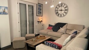 A living room with a beige sofa, a wooden coffee table, and a large wall clock.