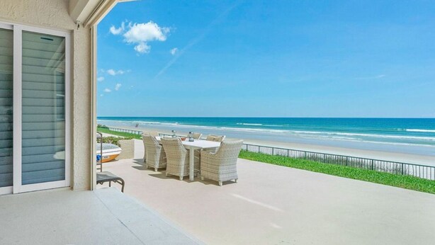 Ein Balkon mit Blick auf den Strand, Gartenmöbel und ein Boot am Ufer.