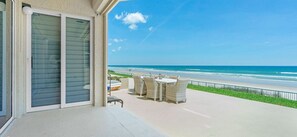 A balcony with a view of the beach, outdoor furniture, and a boat on the shore. - Luxury ground floor apartment in exclusive Ponce inlet (Ponce Inlet)