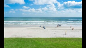 Ein Strand mit Menschen, die Volleyball spielen, bewölkter Himmel und ruhigen Meereswellen.