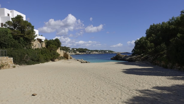 A sandy beach with white buildings and rocky outcrops. - Beautiful beachfront private villa with swimming pool in Cala d'Or (Cala d'Or)
