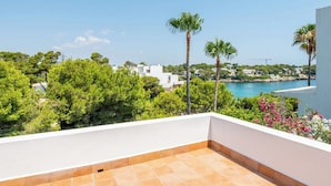 A terrace with a view of a coastal area, including a body of water and buildings in the distance. - Beautiful beachfront private villa with swimming pool in Cala d'Or (Cala d'Or)