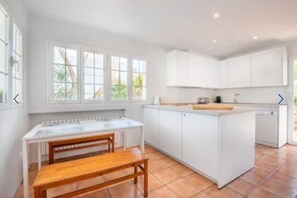 Enjoy cooking in this well-equipped kitchen with a large island, wooden bench, and ample counter space.