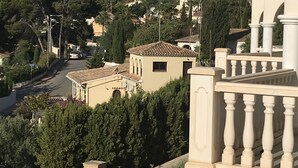 Un quartier résidentiel caractérisé par une architecture traditionnelle, notamment un bâtiment doté d’un toit en tuiles et d’un balcon orné de balustres.