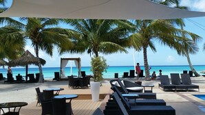 A beachside resort with lounge chairs, a thatched-roof structure, and a view of the ocean. - Appartamento vista mare (Bayahibe)