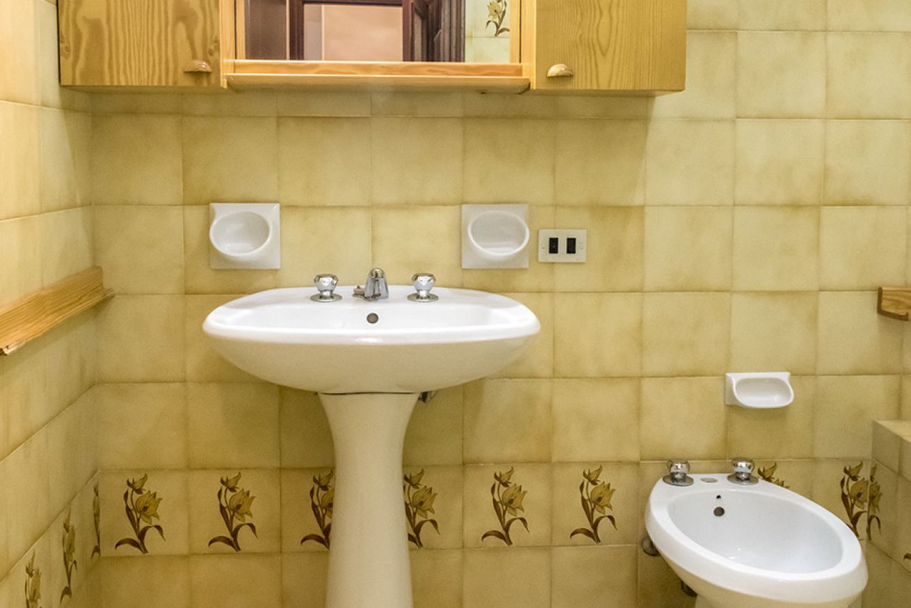 Une salle de bain avec un lavabo sur colonne, un bidet et un miroir au-dessus du lavabo.