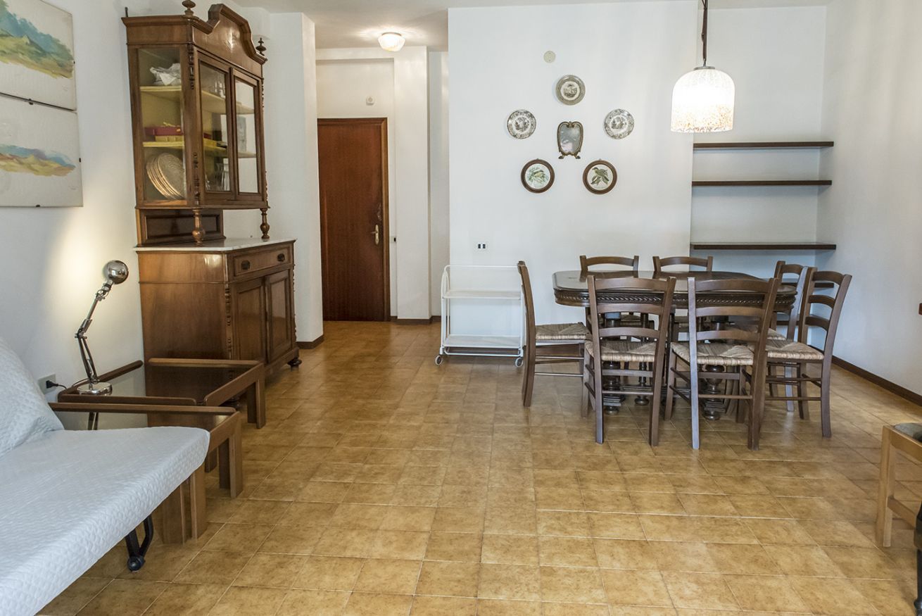 A dining area with a wooden table and chairs, a cabinet, and a wall-mounted light fixture.