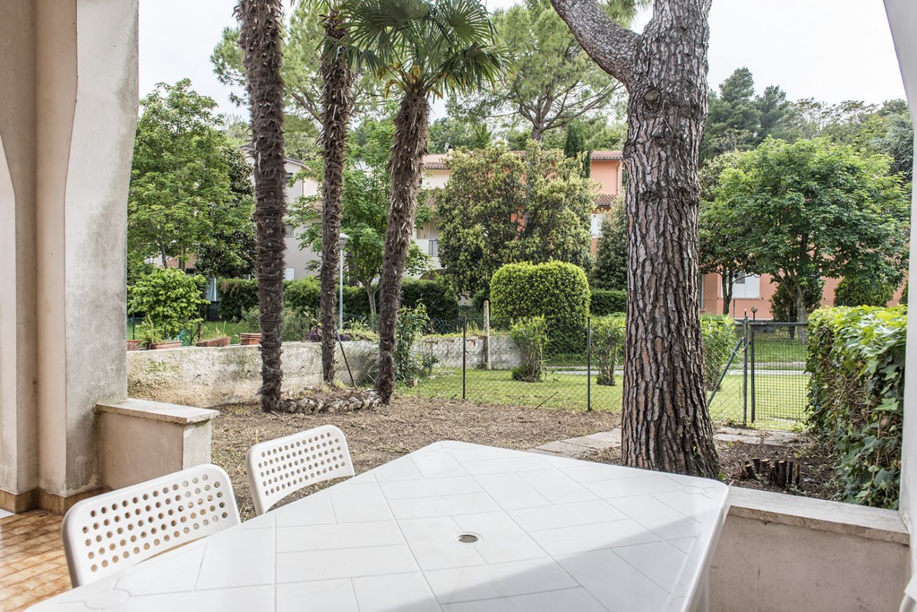A patio area with a table and chairs, surrounded by trees and a view of a residential area.