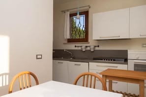 Une cuisine avec des meubles blancs, une table en bois et des chaises.